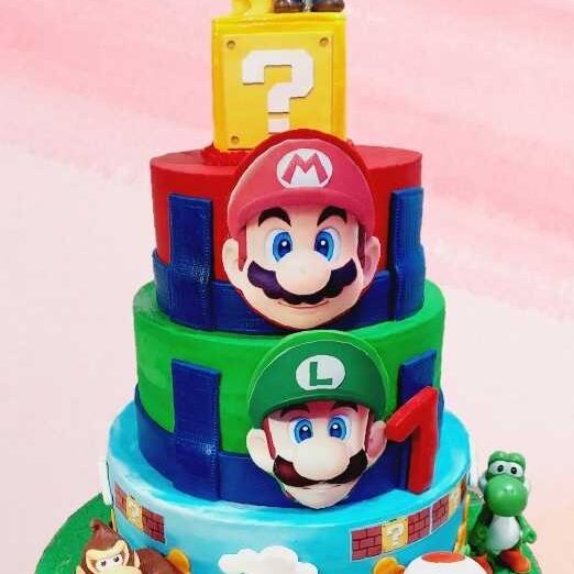 Super Mario Brothers themed birthday cake with layered tiers featuring Mario, Luigi, and other characters
